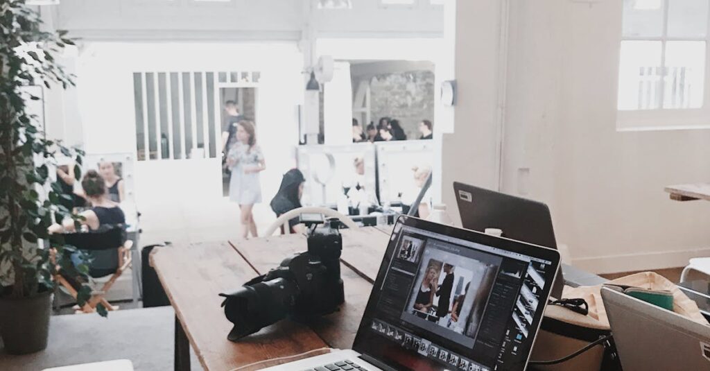 A bright, modern workspace featuring laptops, a camera, and a drawing tablet in an indoor office.