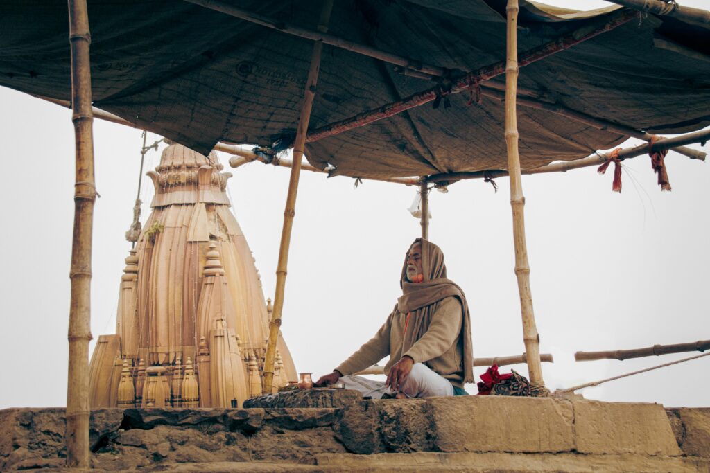 A serene scene of a monk meditating near an ancient temple in Varanasi, India.